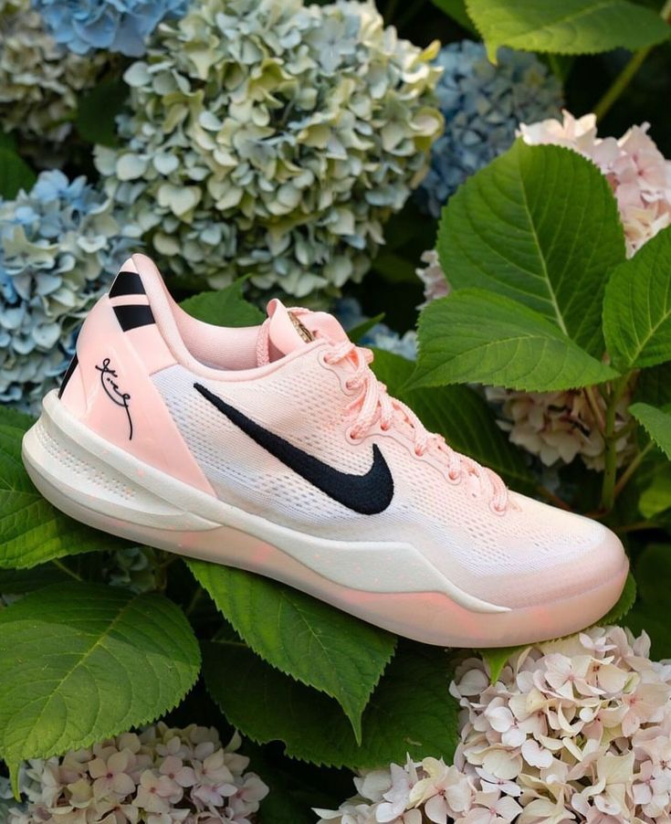 a pair of pink nike shoes sitting on top of flowers