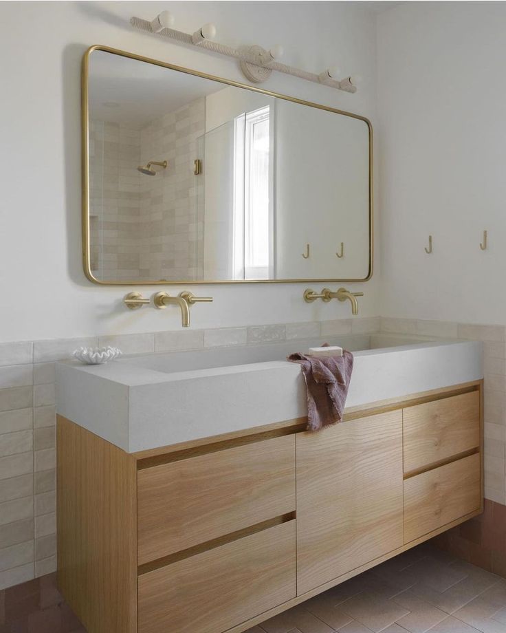 a bathroom with a large mirror above the sink and wooden cabinetry on the side