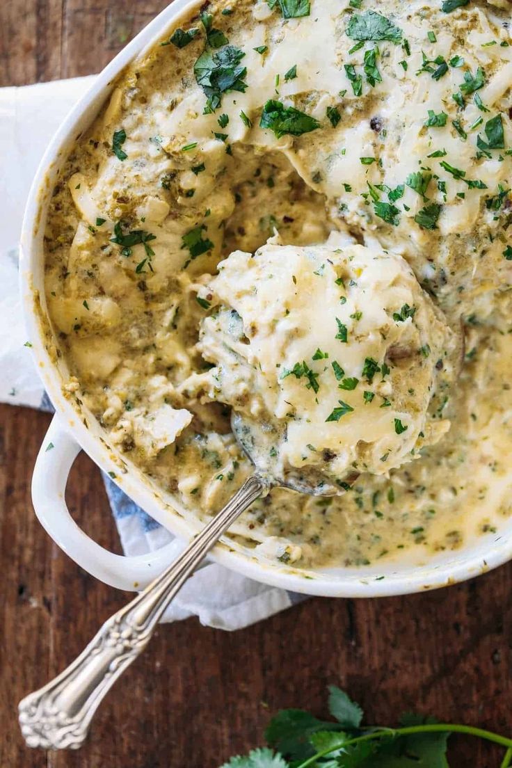 a bowl filled with mashed potatoes covered in gravy and garnished with parsley