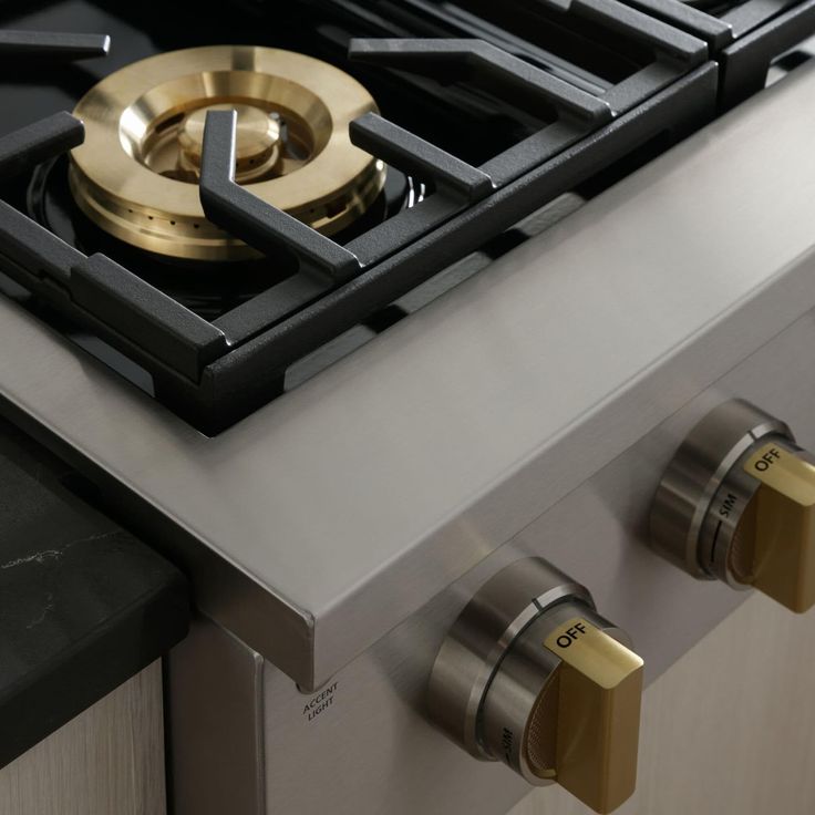 a gas stove with two burners and brass knobs