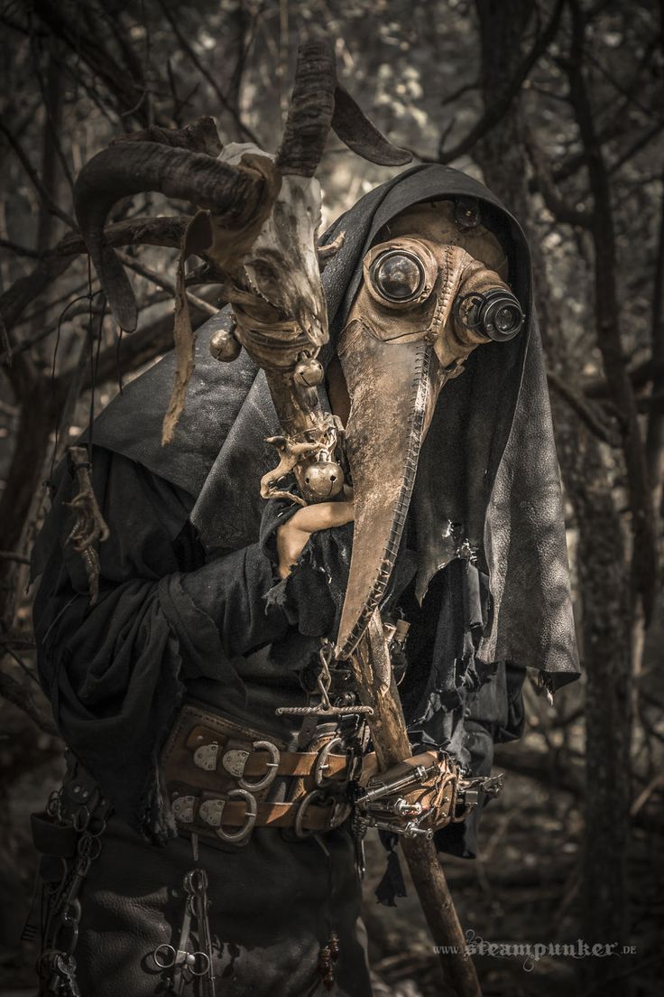 a man dressed in steampunk clothing and gas mask holding an animal's head