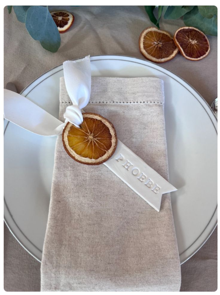 an orange slice is placed on top of a white plate with a ribbon around it