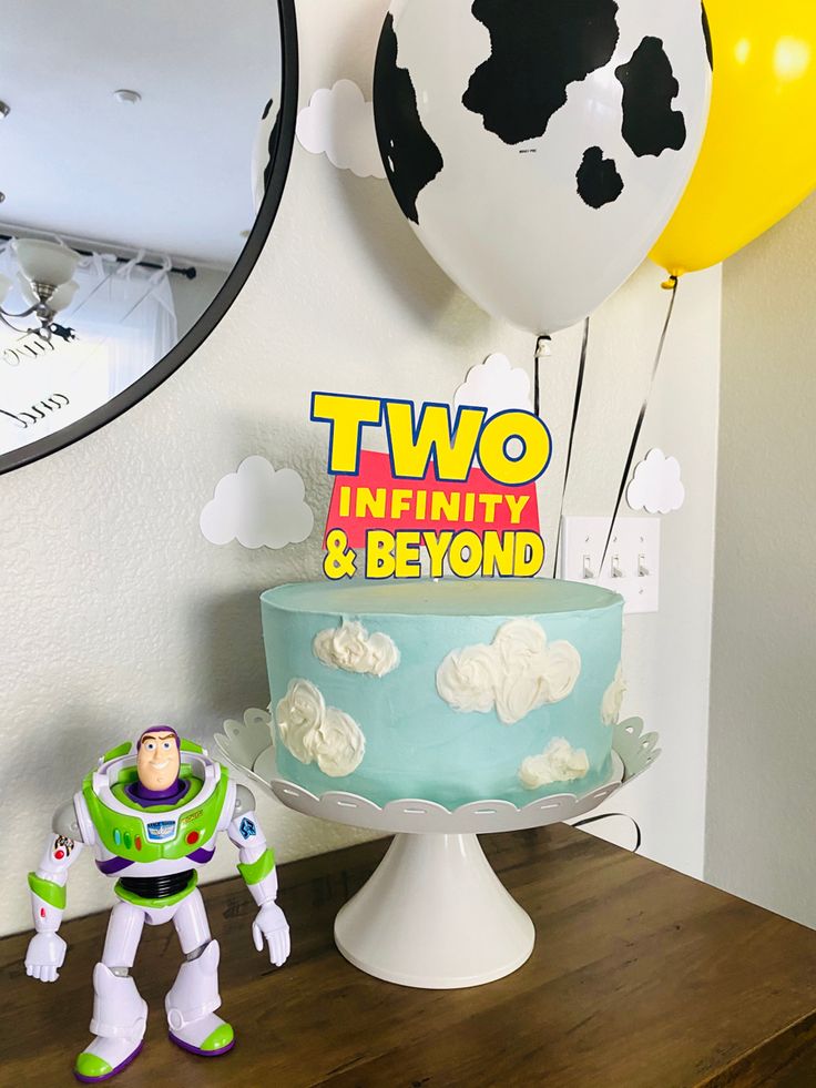 toy story birthday cake with buzz lightyear figure next to it and balloons in the background