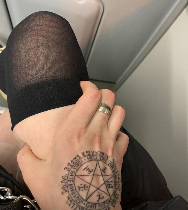 a person with a pentagramil tattoo on their arm and hand, sitting in an airplane