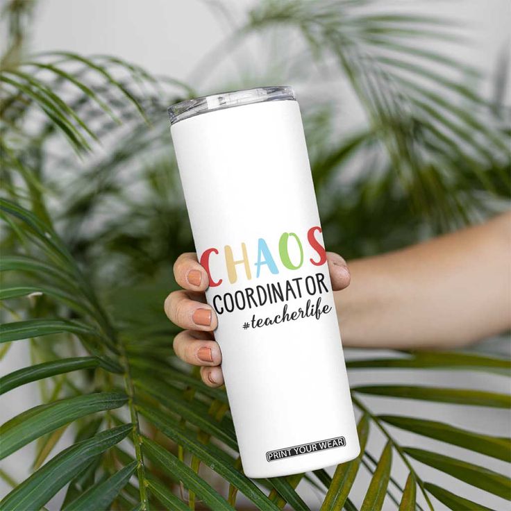 a person holding a white tumbler with the words chaos coordinates on it in front of a plant