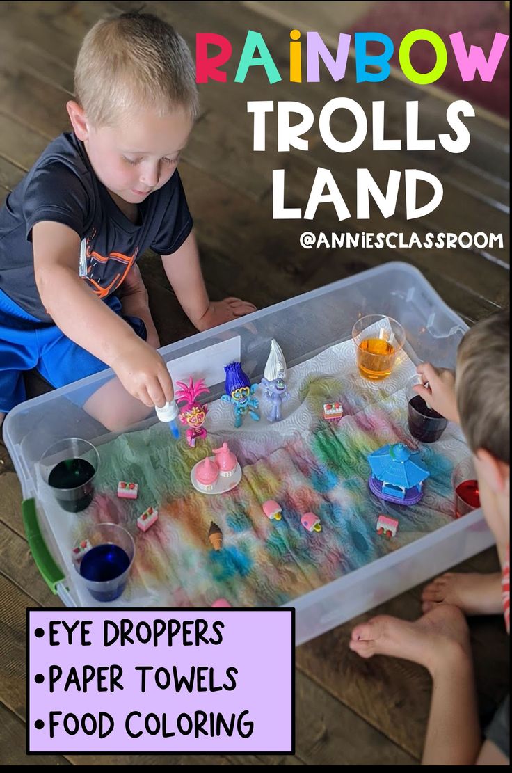 two children playing with rainbow trolls land in an open plastic container on the floor