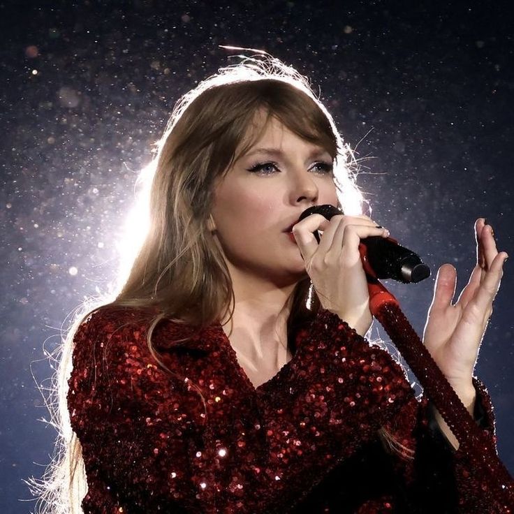 taylor swift singing into a microphone and holding a guitar