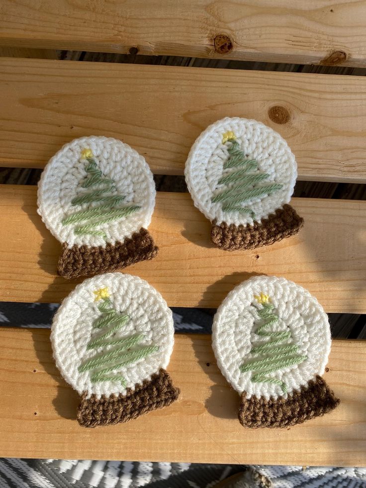 four crocheted christmas tree coasters sitting on top of a wooden table