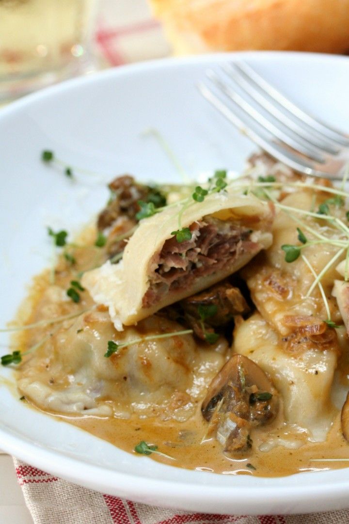 a white plate topped with pasta and meat covered in sauce