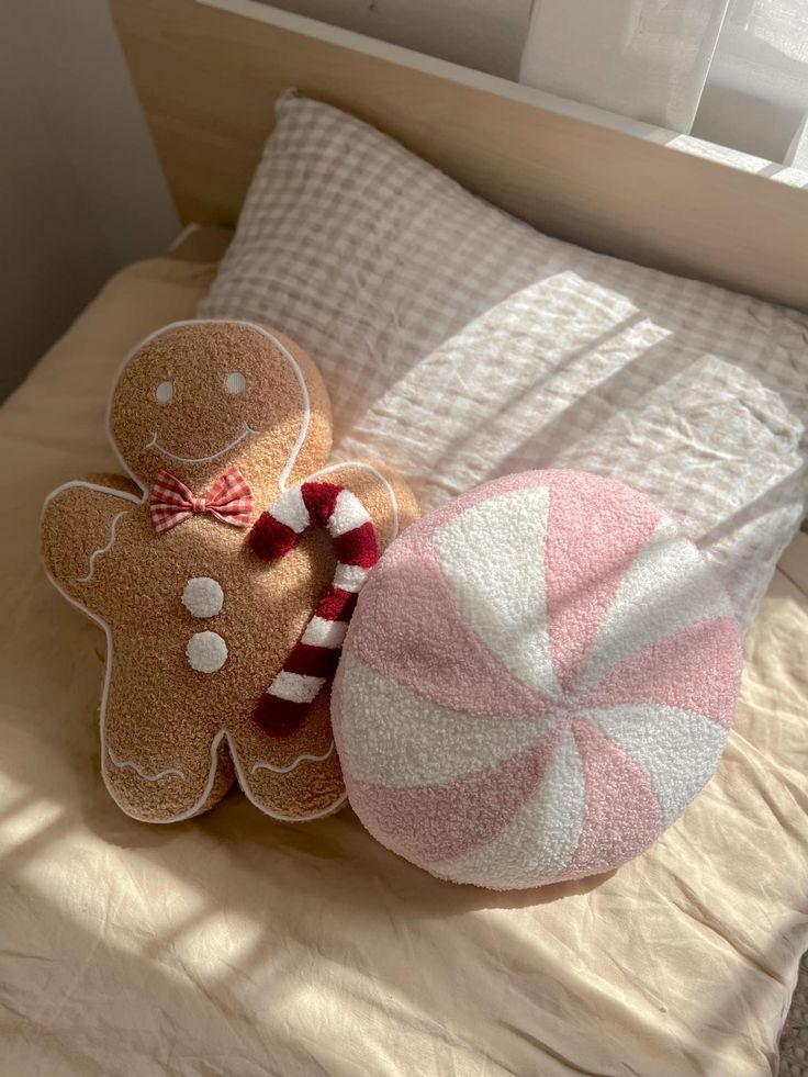 two gingerbreads and a candy cane on a bed