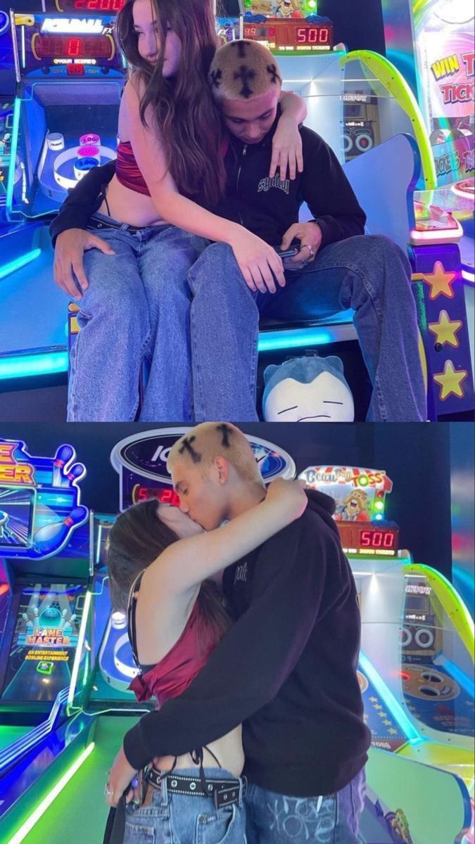 two people sitting on top of each other in front of a video game machine and another person standing behind them