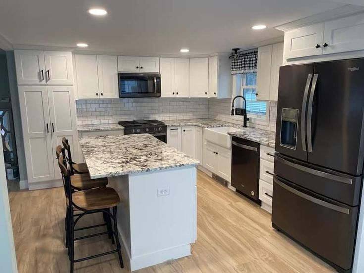 a kitchen with white cabinets and black appliances