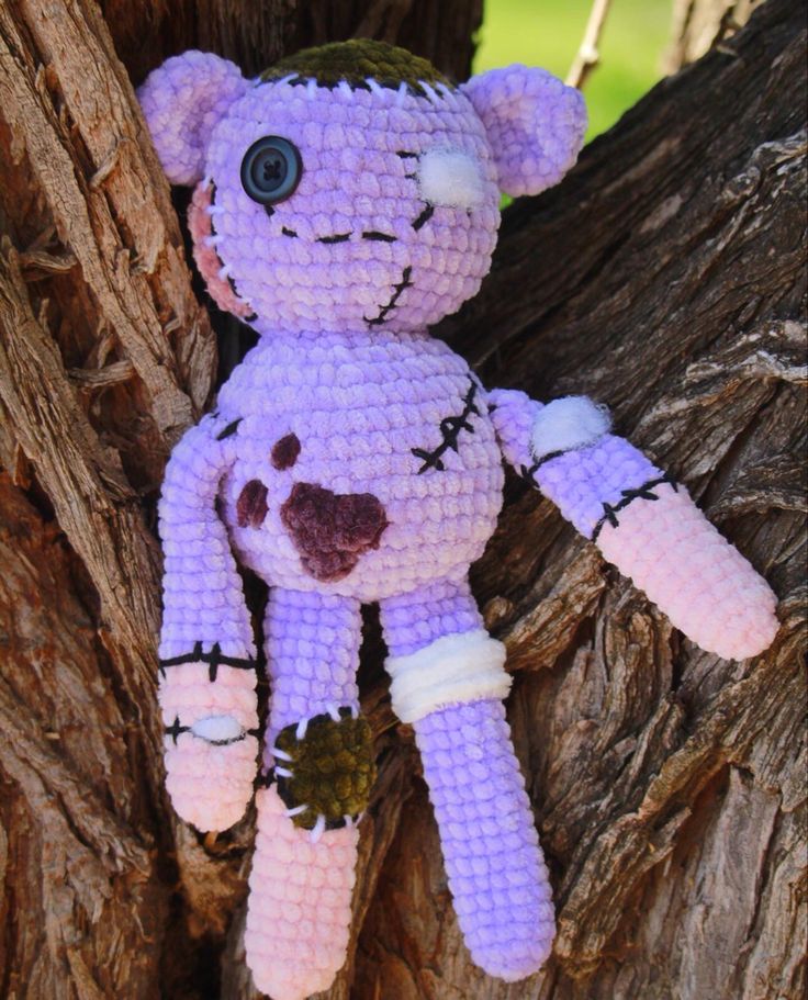 a stuffed animal is sitting in the bark of a tree, wearing purple and white