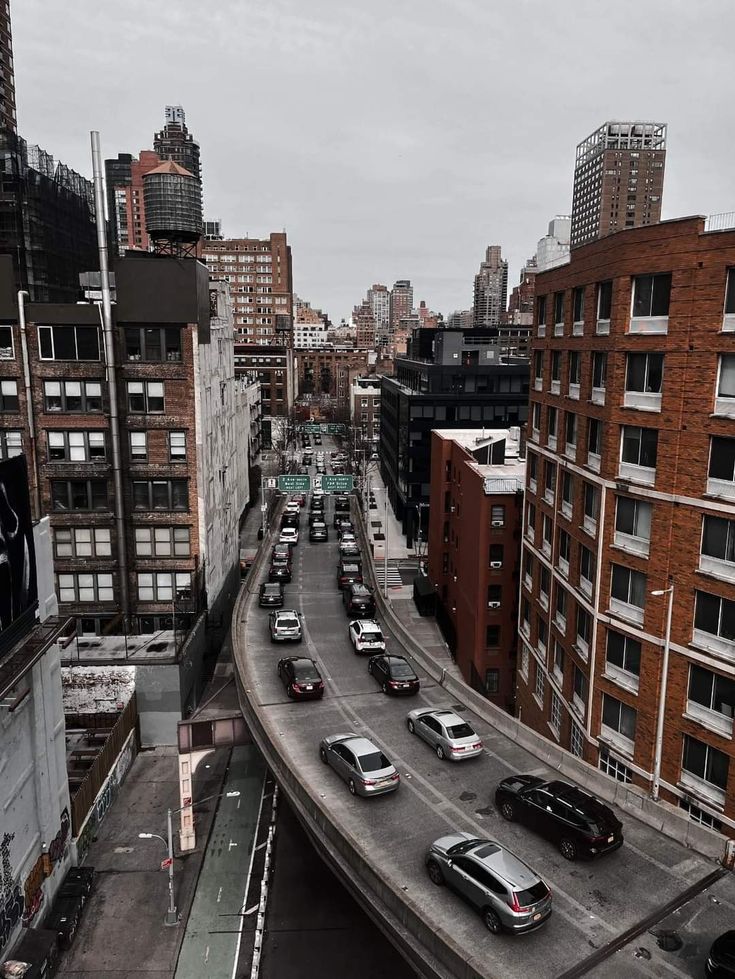 an overhead view of a city street with lots of cars driving on it and tall buildings in the background