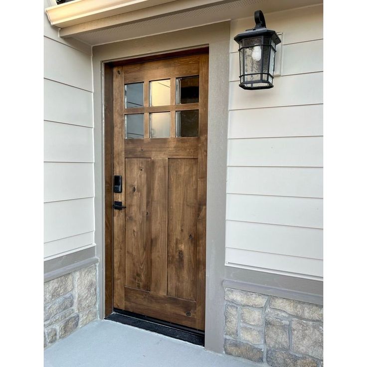 a wooden door on the side of a house with a light hanging from it's side