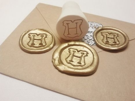 three waxed stamps with the letter h on them are laying on top of an envelope