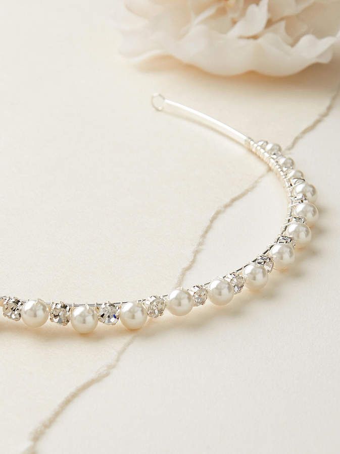 a bridal headband with pearls and swarongs on the side next to a flower