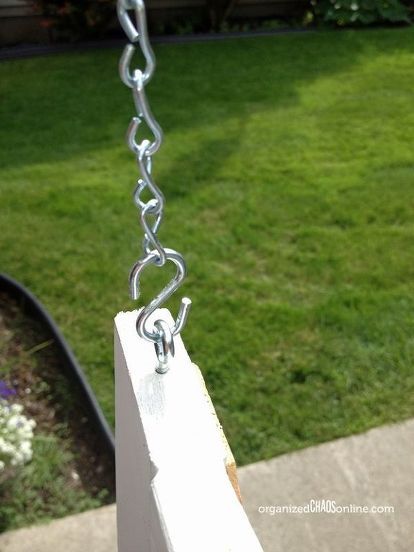 a chain is hanging from the side of a white post in front of a green lawn