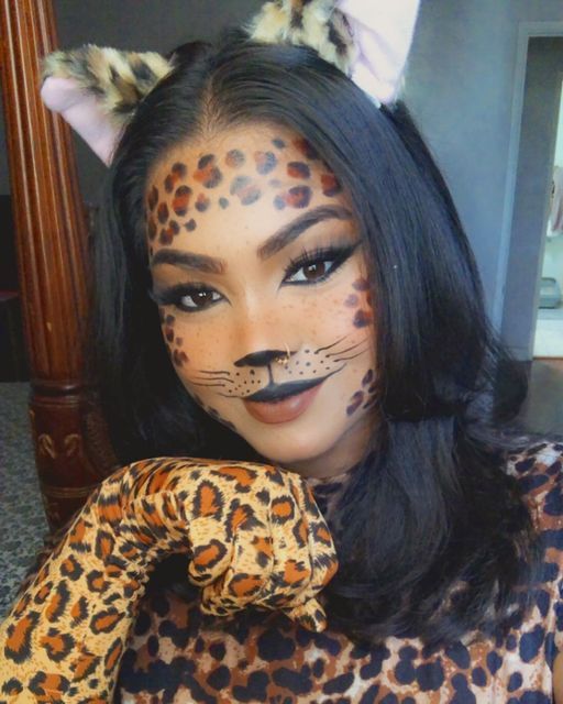 a woman with black hair and cat ears on her head, wearing leopard print makeup