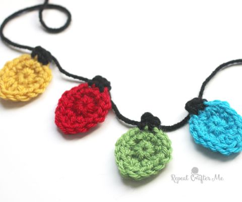 three crocheted ornaments hanging from a string on a white surface with black cord