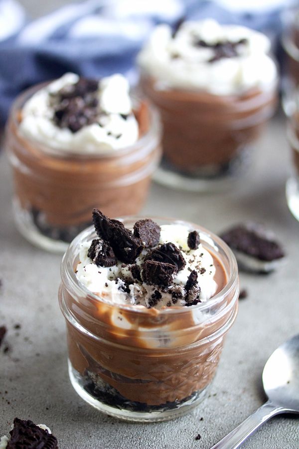 three desserts in small glass jars with spoons