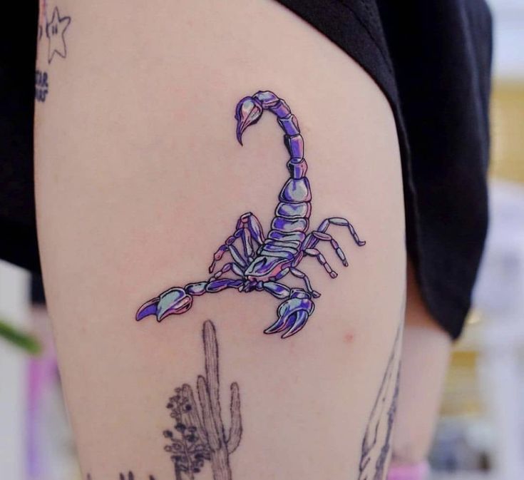 a scorpion tattoo on the back of a woman's leg with cactus and cacti