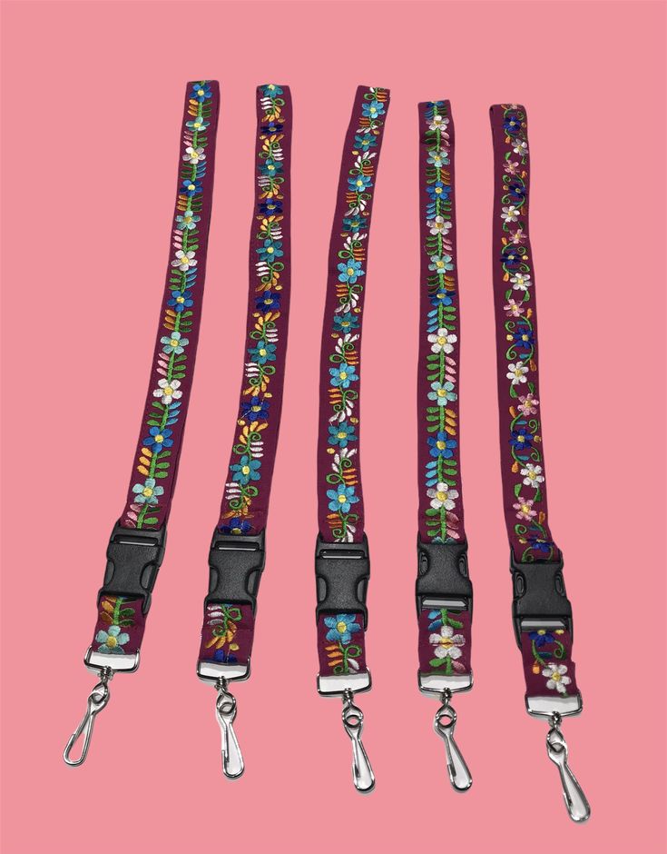 three leashes with flowers on them against a pink background