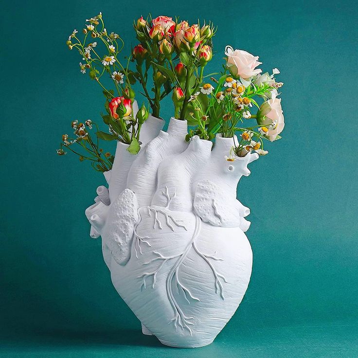 a white vase with flowers in it on a green background