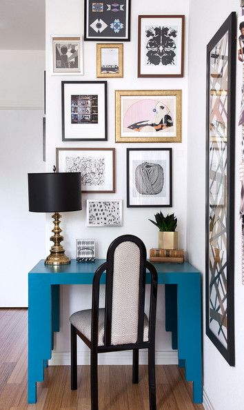 a blue desk with a chair and pictures on the wall