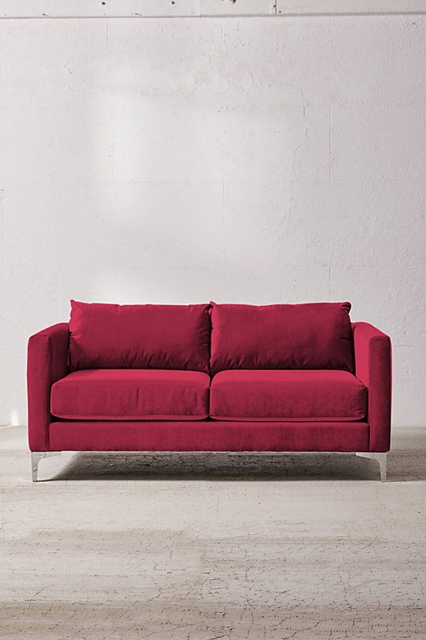 a red couch sitting in front of a white wall