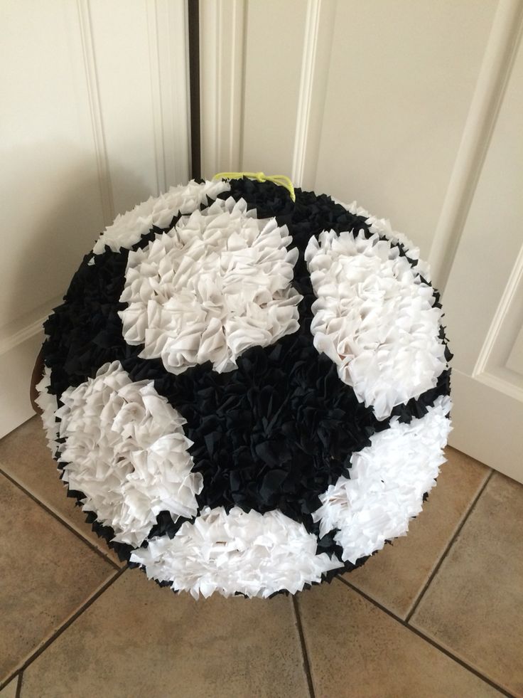 a black and white soccer ball made out of tissue paper on the floor in front of a door