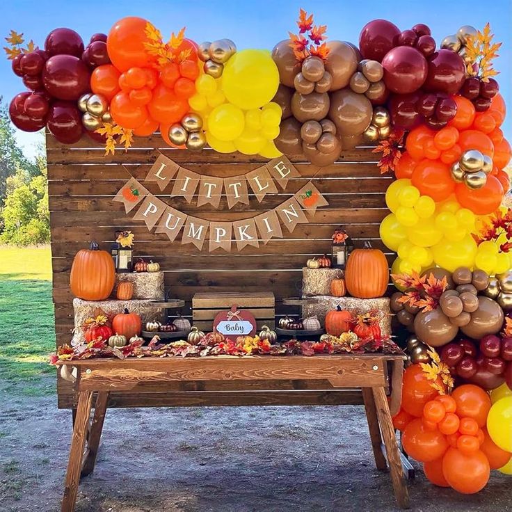 a table topped with lots of balloons next to a sign that says happy pumpkin on it