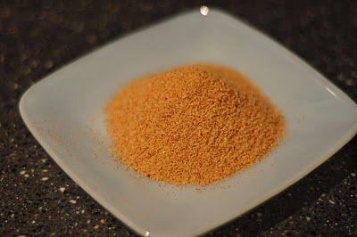 a white plate topped with an orange colored powdered sugar mixture on top of a black counter