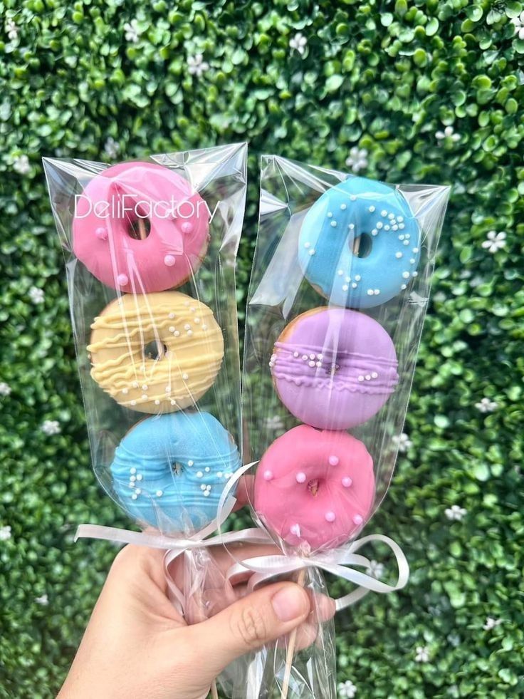 four donuts wrapped in cellophane and tied with ribbon are being held by someone's hand