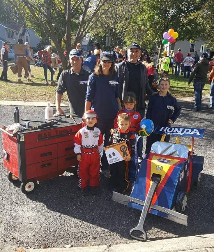 a group of people standing next to each other in front of a red cart filled with items