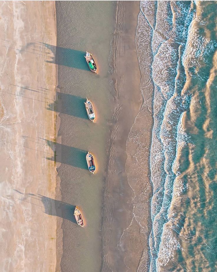 four boats are lined up on the beach