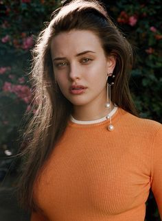 a woman in an orange top is posing for the camera