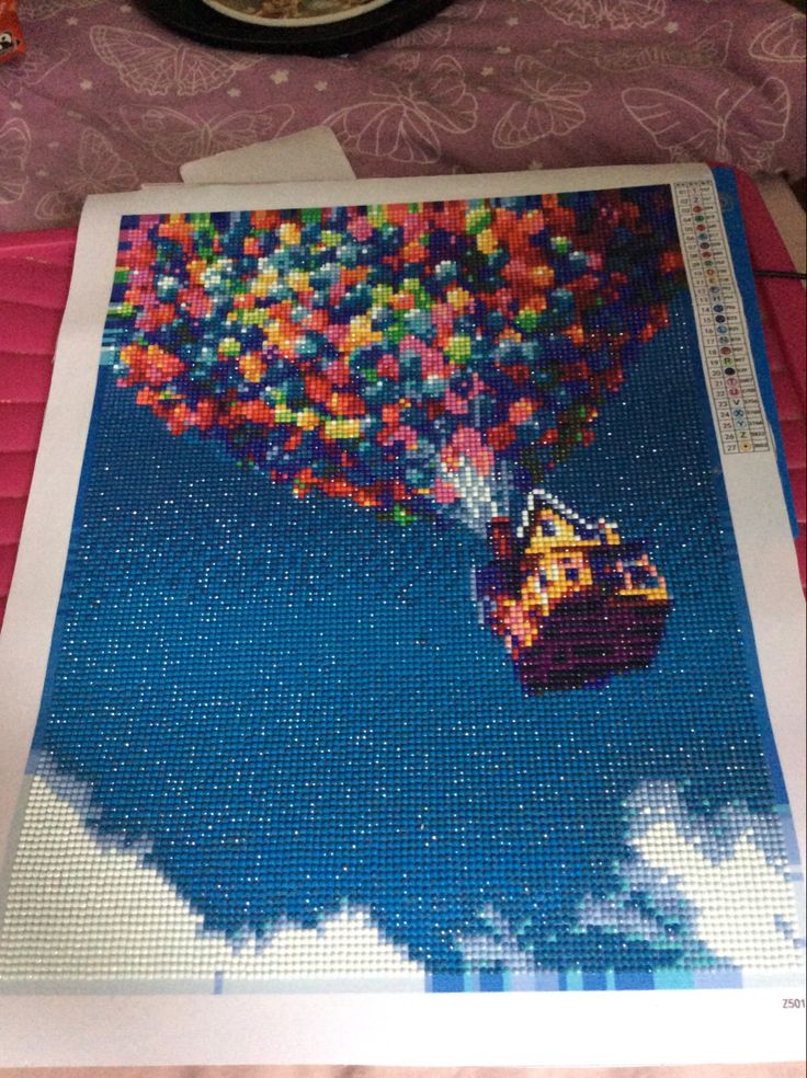 a cross - stitch picture of a hot air balloon being released from the sky by a person