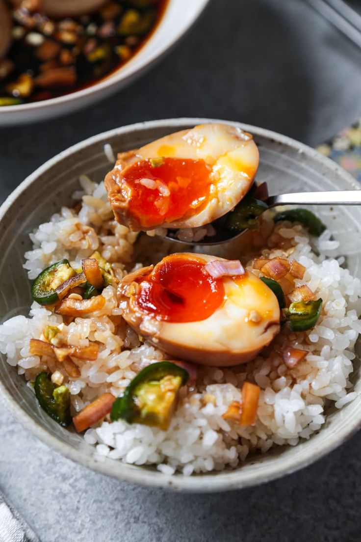 two bowls filled with rice and vegetables covered in sauce