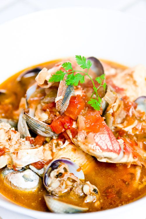 a bowl of soup with clams, tomatoes and parmesan cheese on top