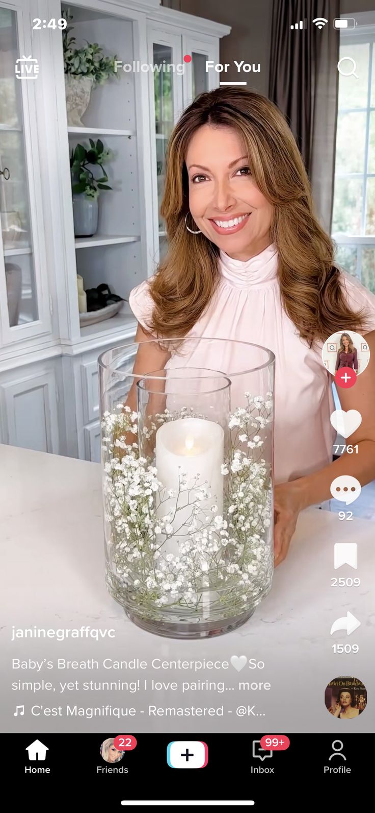 a woman holding a glass vase filled with water and floating flowers on top of a table