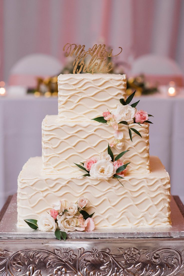 a three tiered wedding cake with pink and white flowers