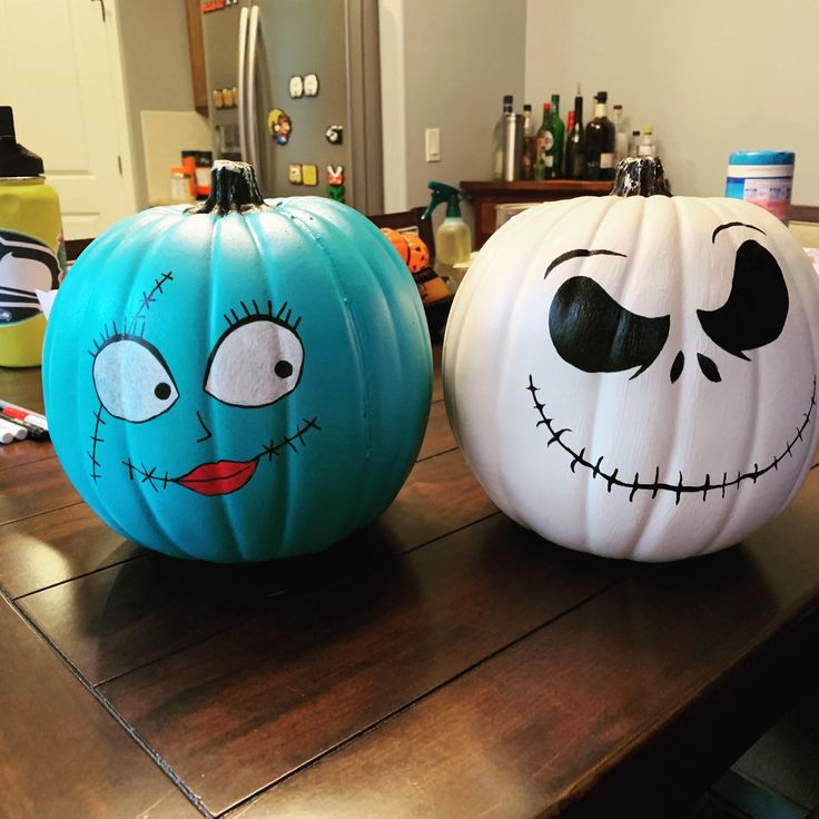 two painted pumpkins sitting on top of a wooden table