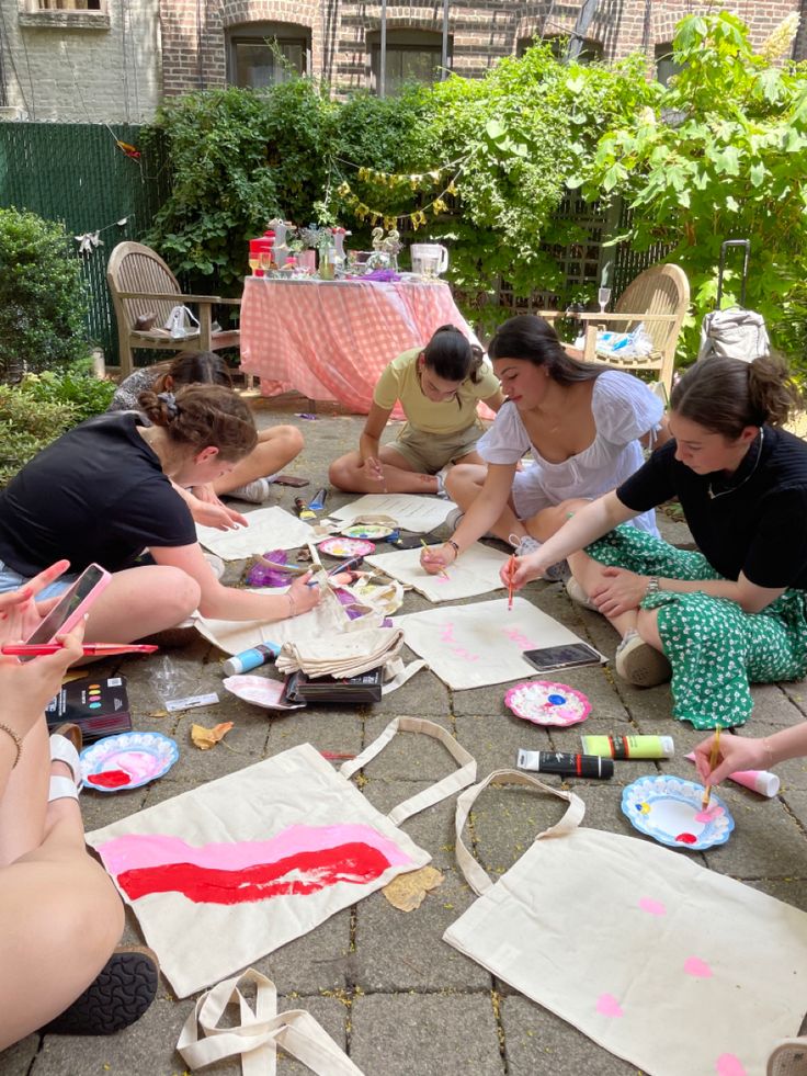 several women sitting on the ground making paper plates