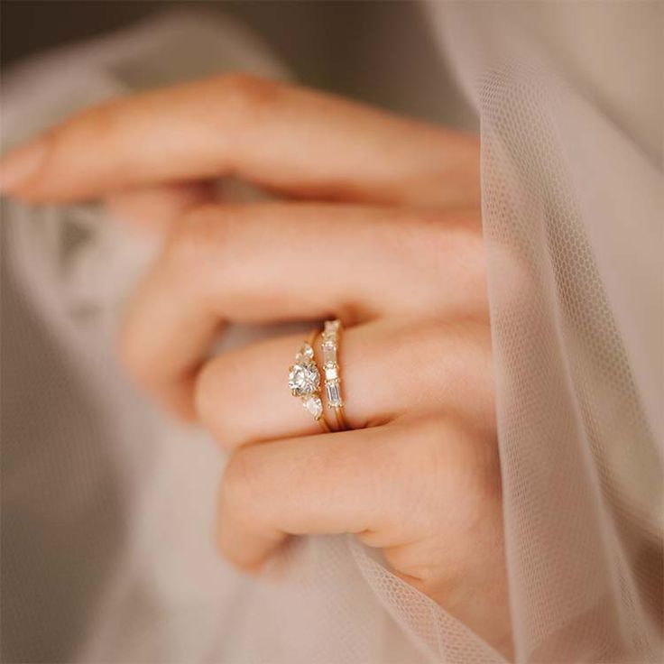 a close up of a person wearing a wedding ring with two stones on the side