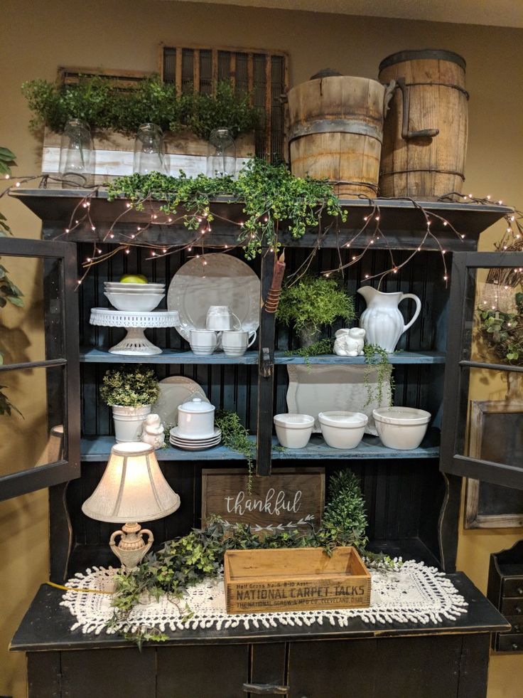 an old fashioned china cabinet with plants and other items on it's display shelf