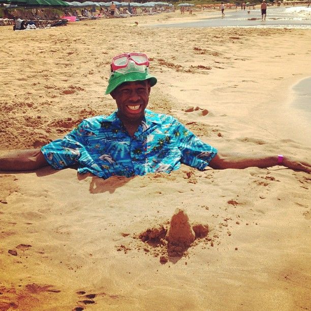 a man sitting in the sand at the beach with his arms spread out and smiling