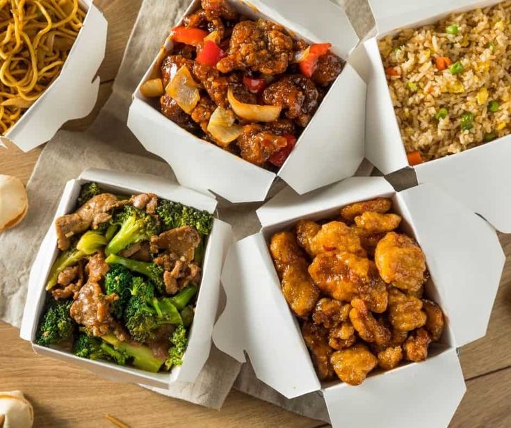 four boxes filled with different types of food sitting on top of a wooden table next to garlic