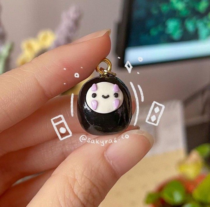 a person holding a small black and white animal charm