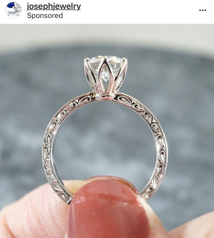 a close up of a person's hand holding a ring with a diamond on it